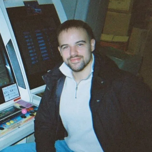 Djordje Janjic sitting beside an arcade cabinet